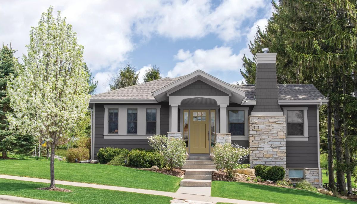 Modern home with dark gray vinyl siding, stone accents, and well-maintained landscaping.