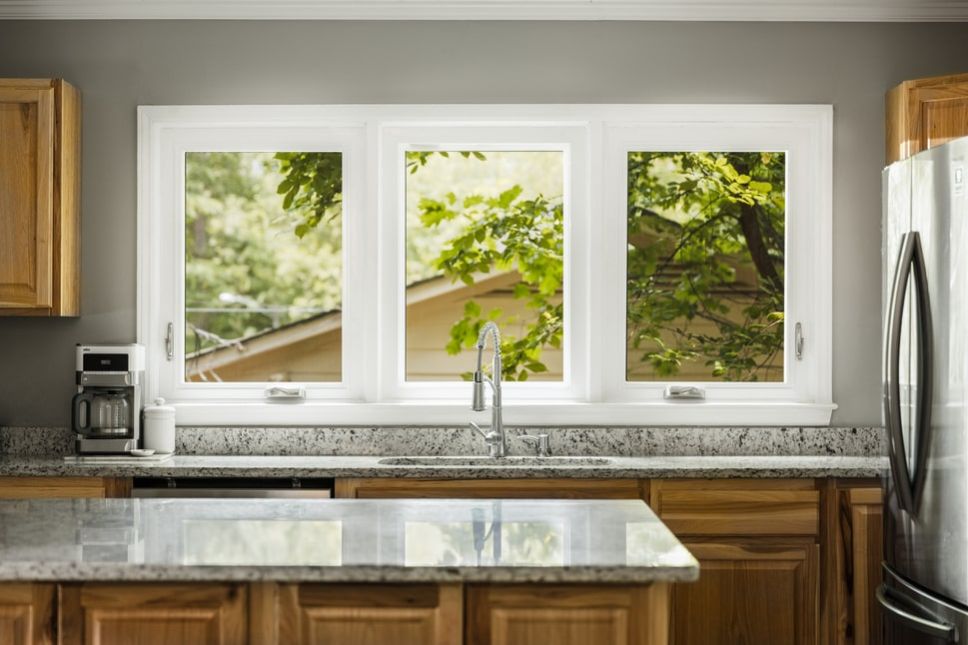 A kitchen with three operable windows behind a sink.