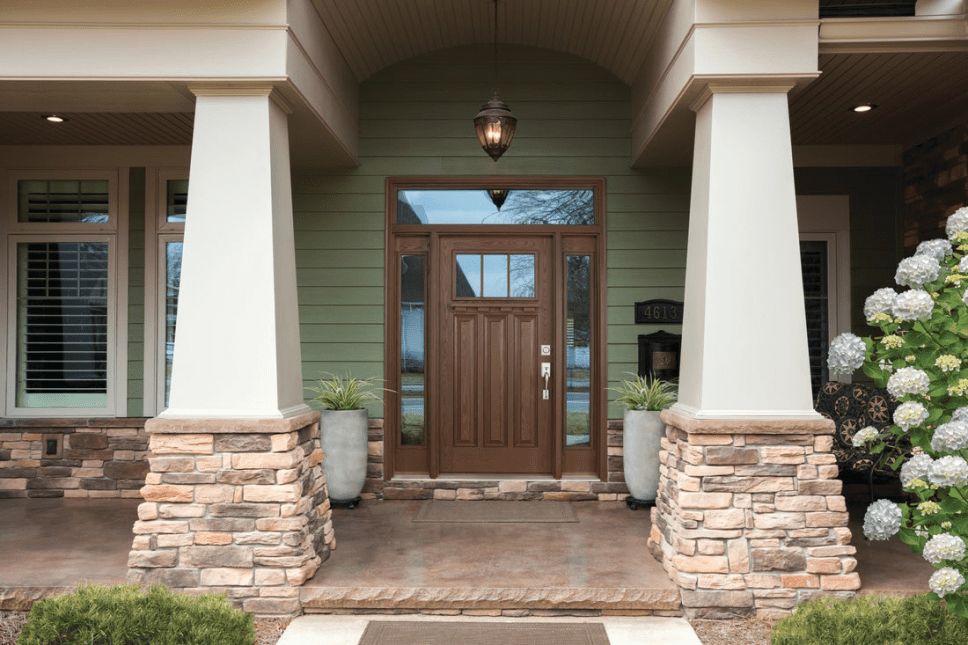 A front porch with a wood-look exterior door with a glass transom and sidelites.