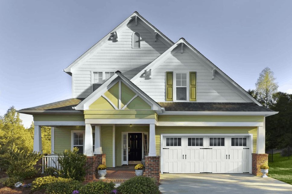 Two-story home with white woodgrain garage doors.
