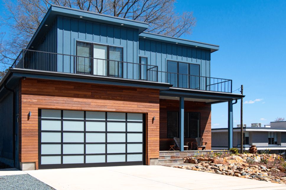 Two-story contemporary home with a black garage door with narrow rectangular glass panels.