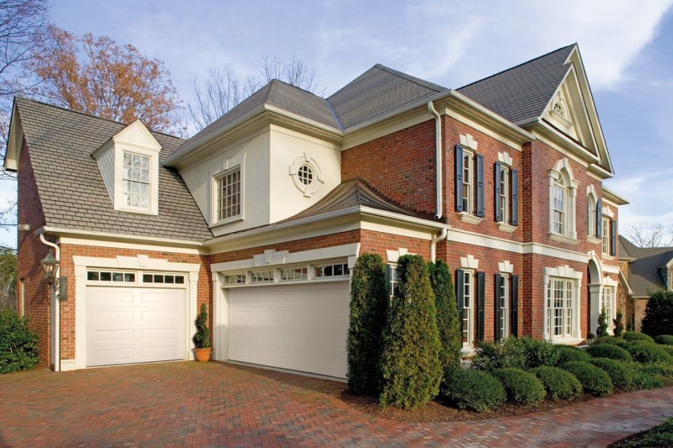 A multi-level residential home with a brick exterior and a white raised panel garage door.
