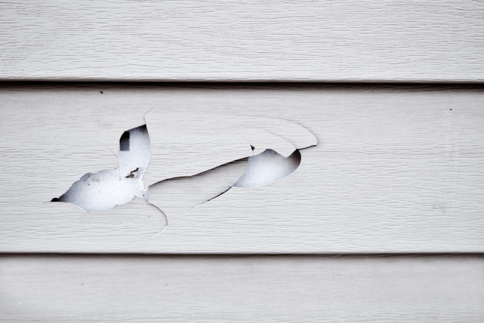 Cracks and damage to vinyl siding that need to be repaired or replaced.