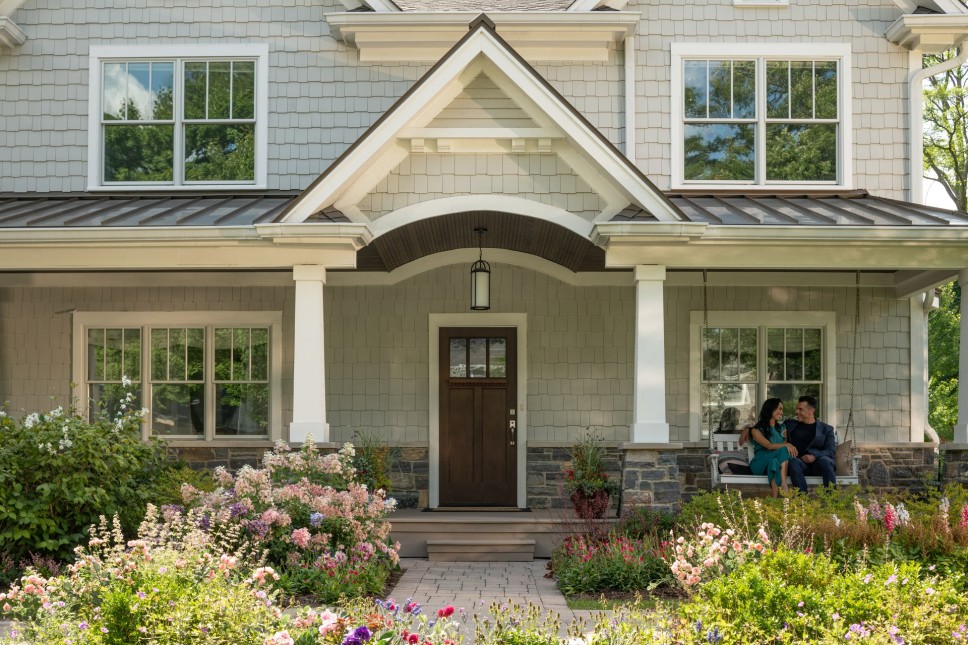 A couple sitting on a swing in front of a house with an energy-efficient entry door