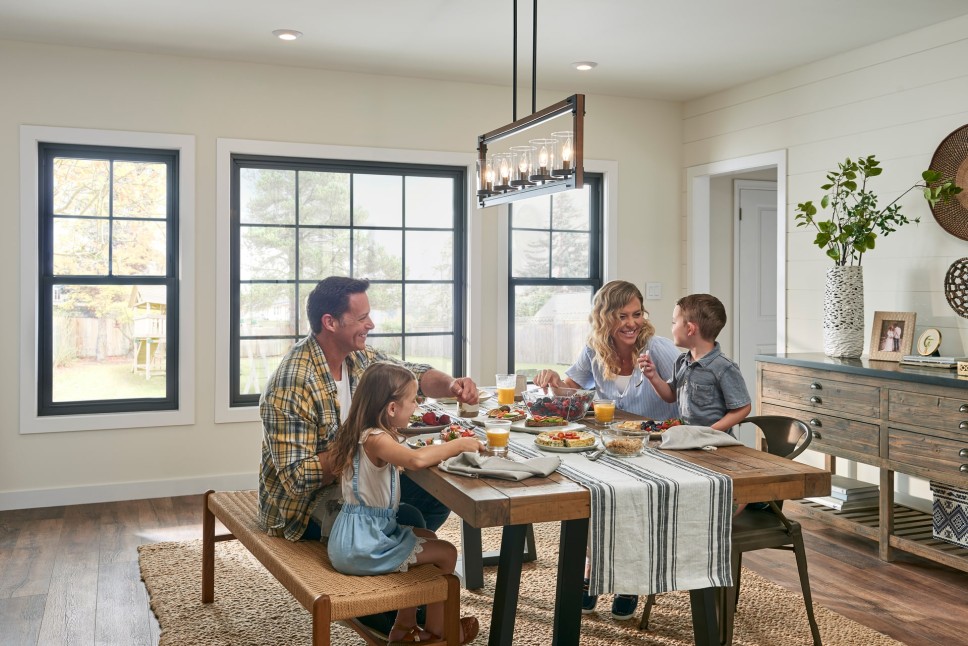Family enjoys breakfast in a naturally lit dining room containing beautiful energy-efficient windows