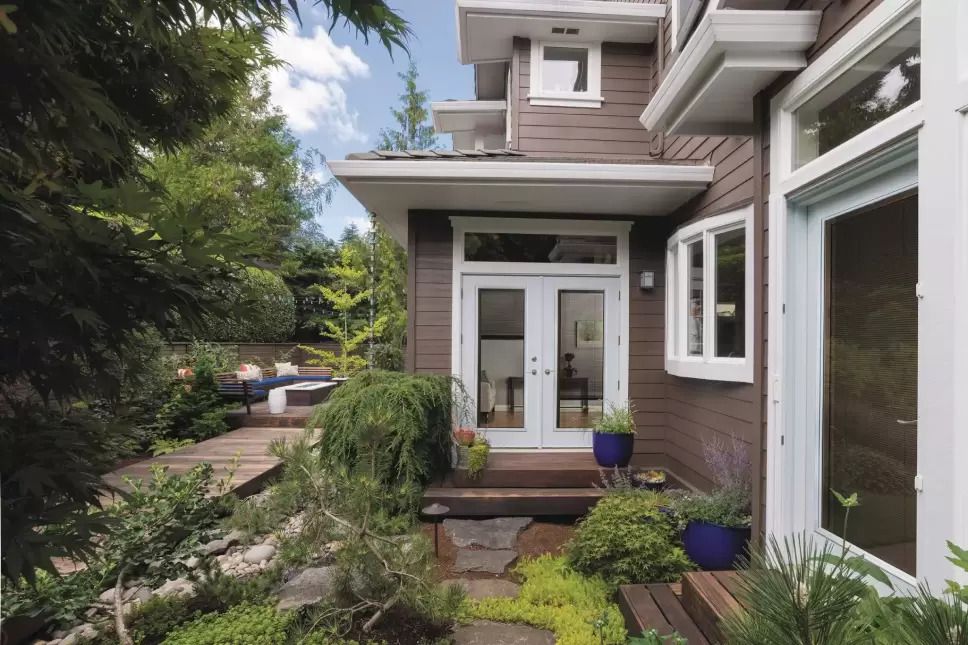 White hinged patio doors connecting a home's interior to its plant-filled outdoor living space.